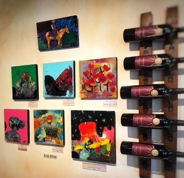 Colorful artwork display with wine bottles