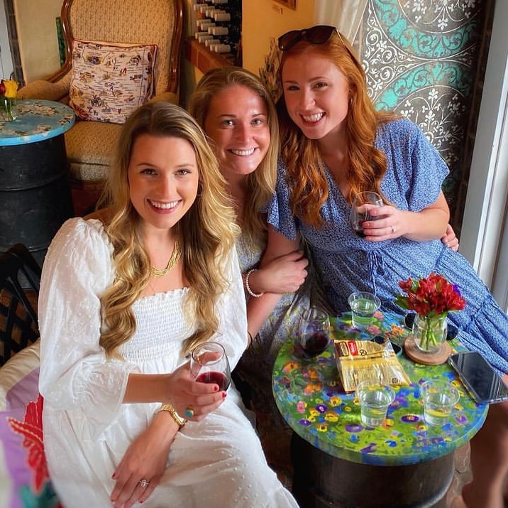 Three women with wine at colorful table Vino Zona