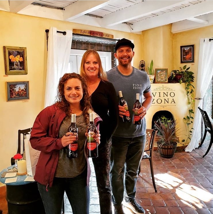 Three guests holding wine bottles at Vino Zona